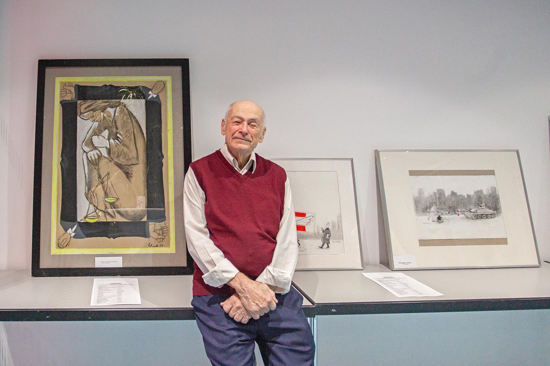 Philipp Heinischs sitzt vor seinen Karikaturen