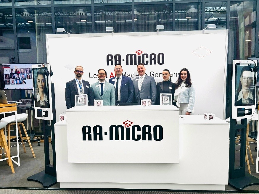 Sechs Personen am RA-MICRO-Messestand auf der LEGAL REVOLUTION 2026, flankiert von zwei digitalen Avatar-Stelen.